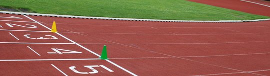 Startbereich der Läufer auf der Tartanbahn. Ein gelbes und ein grünes Hütchen stehen auf der Startlinie